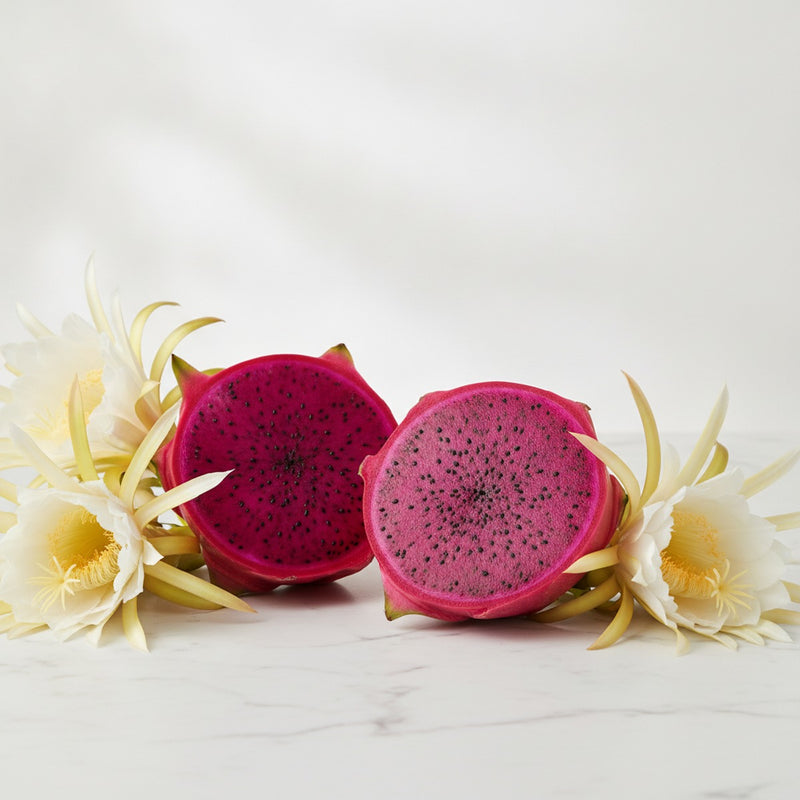 Dragon Fruit — Halved dragon fruit with vibrant magenta flesh and black seeds arranged on white marble, surrounded by fr